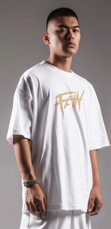 Man wearing oversized white graphic tee with bold sand gold streetwear design on front