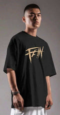 Man wearing black oversized streetwear tee with bold sand gold distressed graphic text